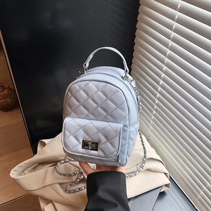 Mini light blue quilted backpack with metal chain strap and turn-lock on trench coat