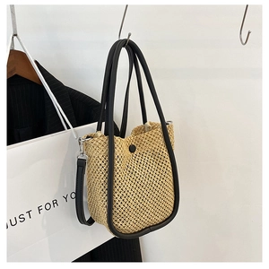 Detail of woven straw bucket bag with black PU leather trim and magnetic snap closure