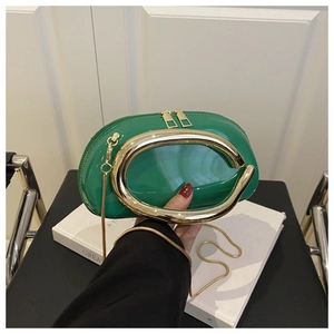 Detail of green patent leather crescent bag with bold gold C-shaped metal handle and chain