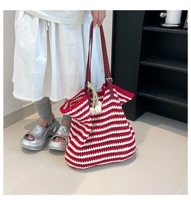 Close-up of a red and white striped knit tote bag with a leather strap and flower charm