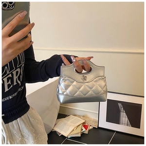 Close-up of a silver quilted mini bag featuring a metal camellia clasp and chic chain strap