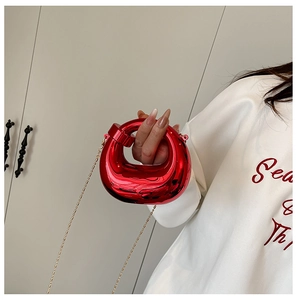 Dettaglio della borsa da sera in acrilico rosso con finitura metallica e catena dorata