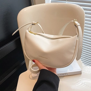 Minimalist beige pebble leather half-moon shoulder bag with adjustable strap and zipper