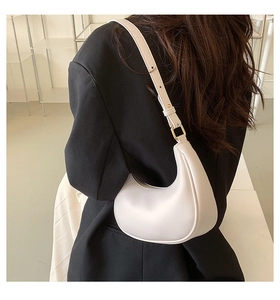 Side view of cream white hobo bag with adjustable strap worn on black blazer outfit