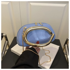 Detail of light blue patent leather bag with oval gold handle on white book