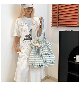 Detail of blue and white striped knit tote bag with woven tulip charms and slim shoulder strap