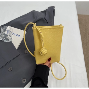 Details einer hellgelben Mini-Eimertasche aus strukturiertem Leder mit geknotetem Schultergurt