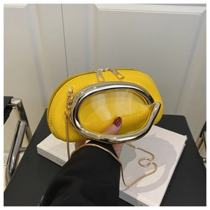 Detail of glossy yellow patent leather handbag with silver U-handle and fine gold chain strap