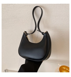 Detail of a sleek black crescent moon shoulder bag featuring smooth leather and zipper close