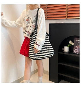 Detail of hand-woven striped tote bag with black leather strap and puppy embroidery