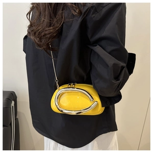 Close-up of bright yellow patent leather crossbody bag with oversized silver metal ring