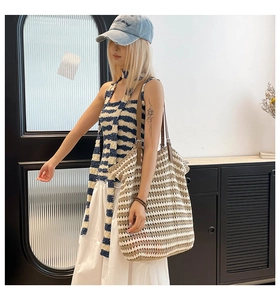 Detail of large woven striped tote bag with brown leather straps for summer style