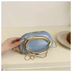 Detail view of light blue patent leather clutch featuring a large oval gold metal handle