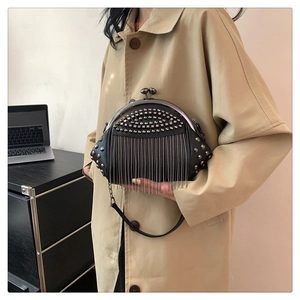 Nahaufnahme einer schwarzen Retro-Muscheltasche mit Metallnieten und Kettenquasten