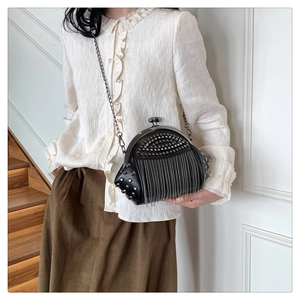 Detailaufnahme der schwarzen Muscheltasche mit Nieten und Metallfransen-Ketten