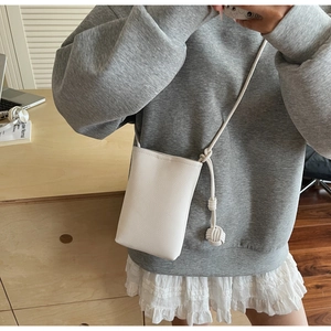 Close-up of white lychee pattern leather phone bag with stylish knotted rope strap detail