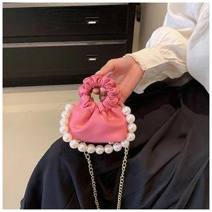 Close-up of pink ruched cloud bag with large pearl handle and fine gold chain strap