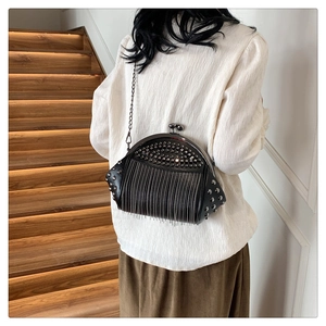 Detail einer schwarzen Vintage-Muscheltasche mit Metallnieten und langen Fransen