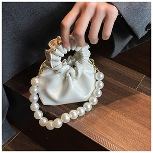 Detailed close-up of cream cloud mini bag featuring large pearl handle and pleated texture