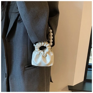 Close-up of a white mini cloud bag with pleated PU leather and a large pearl handle strap