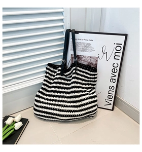 Close-up of hand-woven black and white striped tote bag with adjustable leather strap
