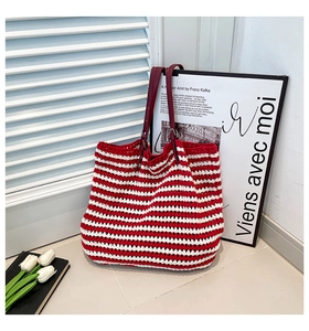 Detail of red and white striped hand-woven tote bag with leather straps and metal buckles