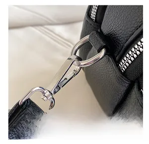 Close-up of silver metal hook and D-ring on black lychee texture leather shoulder bag