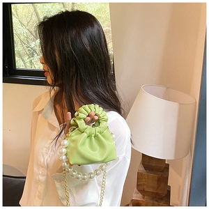 Detail of mint green ruched cloud bag featuring decorative pearls and gold chain strap