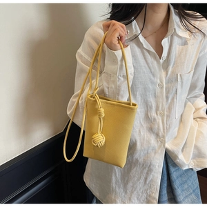 Detail of yellow lychee leather mini bucket bag with handmade woven knot on shoulder strap