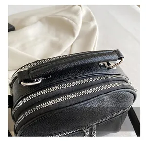 Close-up of black lychee grain leather handbag featuring multi-layer silver zippers