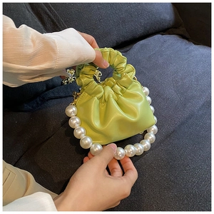 Detail of bright green mini cloud bag with pearl trim and scrunchie handle on sofa