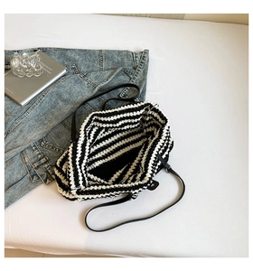 Detailed view of hand-woven striped bag with thick knit texture and leather strap