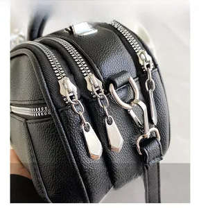 Detail shot of multi-layer silver metal zippers on black lychee textured leather bag