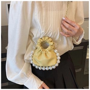 Detail view of yellow cloud bag featuring pearl trim and elegant gold chain strap