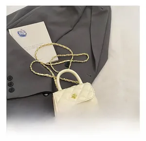 Detailed view of mini cream quilted crossbody bag with gold floral clasp on grey blazer