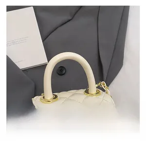 Detail of cream quilted handbag featuring a golden camellia clasp and chain strap