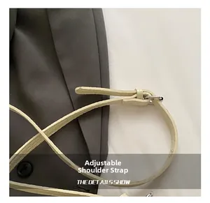 Detail shot of the adjustable cream leather strap with silver buckle on the bucket bag