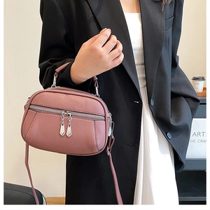 Detail of dusty rose pebble leather handbag with dual zippers and silver metallic pulls