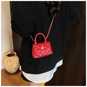 Detailed view of mini red quilted crossbody bag with golden camellia floral metal clasp