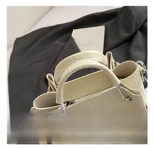 Close-up of beige crocodile pattern bucket bag with silver hardware and smooth handle