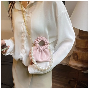 Detail of pink pleated mini cloud bag featuring decorative pearl handle and chain strap
