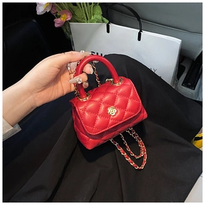 Detail of red quilted mini bag with flower lock and golden chain strap held by hand