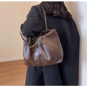 Detail der dunkelbraunen Ledertasche mit Falten und goldener Kette an der Schulter