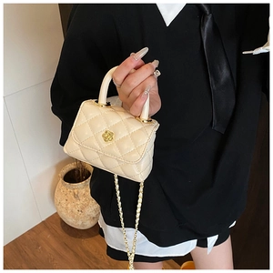 Detail of a mini quilted cream handbag with a gold floral twist lock and elegant top handle