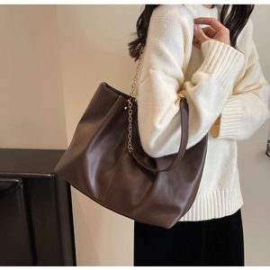 Detail der braunen Leder-Shopper-Tasche mit breitem Riemen und goldener Kette