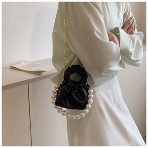 Mini black cloud bag with pearl handle and gold chain strap shown on person