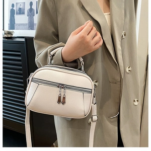 Detail of soft beige pebbled leather texture and double zipper design on the shoulder bag