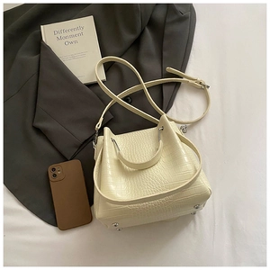 Top view of cream crocodile pattern bucket bag with metal studs and elegant accessories