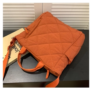 Détail d'un cabas matelassé orange avec motif à losanges et bandoulière large réglable
