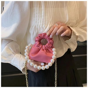 Detailed view of mini pink pleated cloud bag with large pearl strap and gold chain